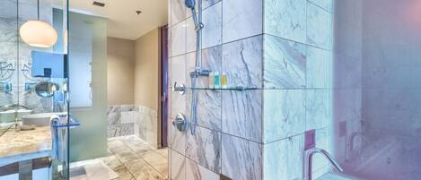Un bany modern amb rajoles de marbre, una cabina de dutxa de vidre i un lavabo amb mirall.