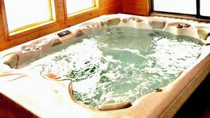 Un jacuzzi en una cabaña de madera con ventanas grandes.