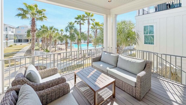 Un espacio al aire libre techado con muebles de mimbre, piscina y vistas de los edificios circundantes.