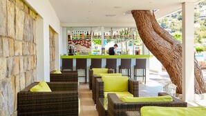 A bar area with wicker furniture and a bartender. - Canyamel Garden Apartments (Capdepera)