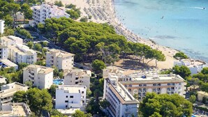 A coastal town with a beach, multiple hotel buildings, and a swimming pool. - Canyamel Garden Apartments (Capdepera)
