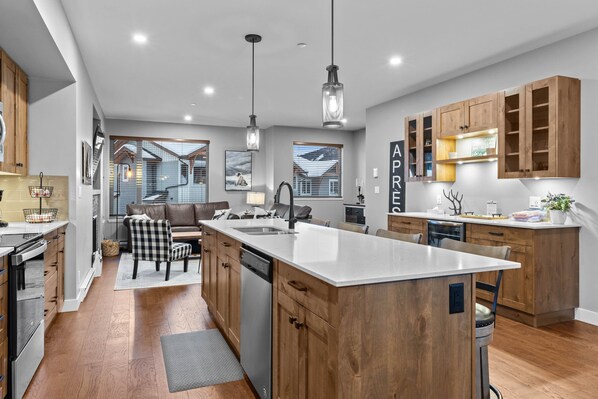 A modern kitchen with wooden cabinets, a central island, and pendant lighting.