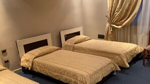 Ein Hotelzimmer mit zwei Betten, jeweils mit Kopfteil und einer beige farbenen Bettdecke.