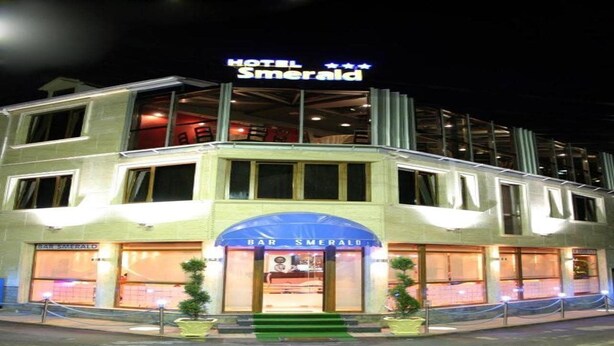 Ein mehrstöckiges Hotel mit einer gut sichtbaren Bar namens 'Bar Smerald' im Erdgeschoss.