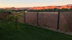 Quintal cercado com uma pequena árvore e vista desobstruída de uma cordilheira ao fundo.