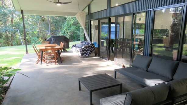 Une terrasse extérieure avec une table à manger, des chaises, un canapé et une petite table d’appoint.
