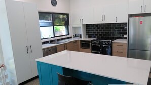 Une cuisine moderne avec des meubles de couleur blanche et turquoise, un réfrigérateur en acier inoxydable, une cuisinière et un four à micro-ondes.