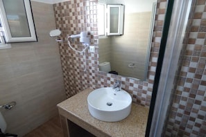 A bathroom with a checkered tile backsplash, a round sink, a handheld showerhead, and a mirror. - Paradiso Apartments (Corfu)