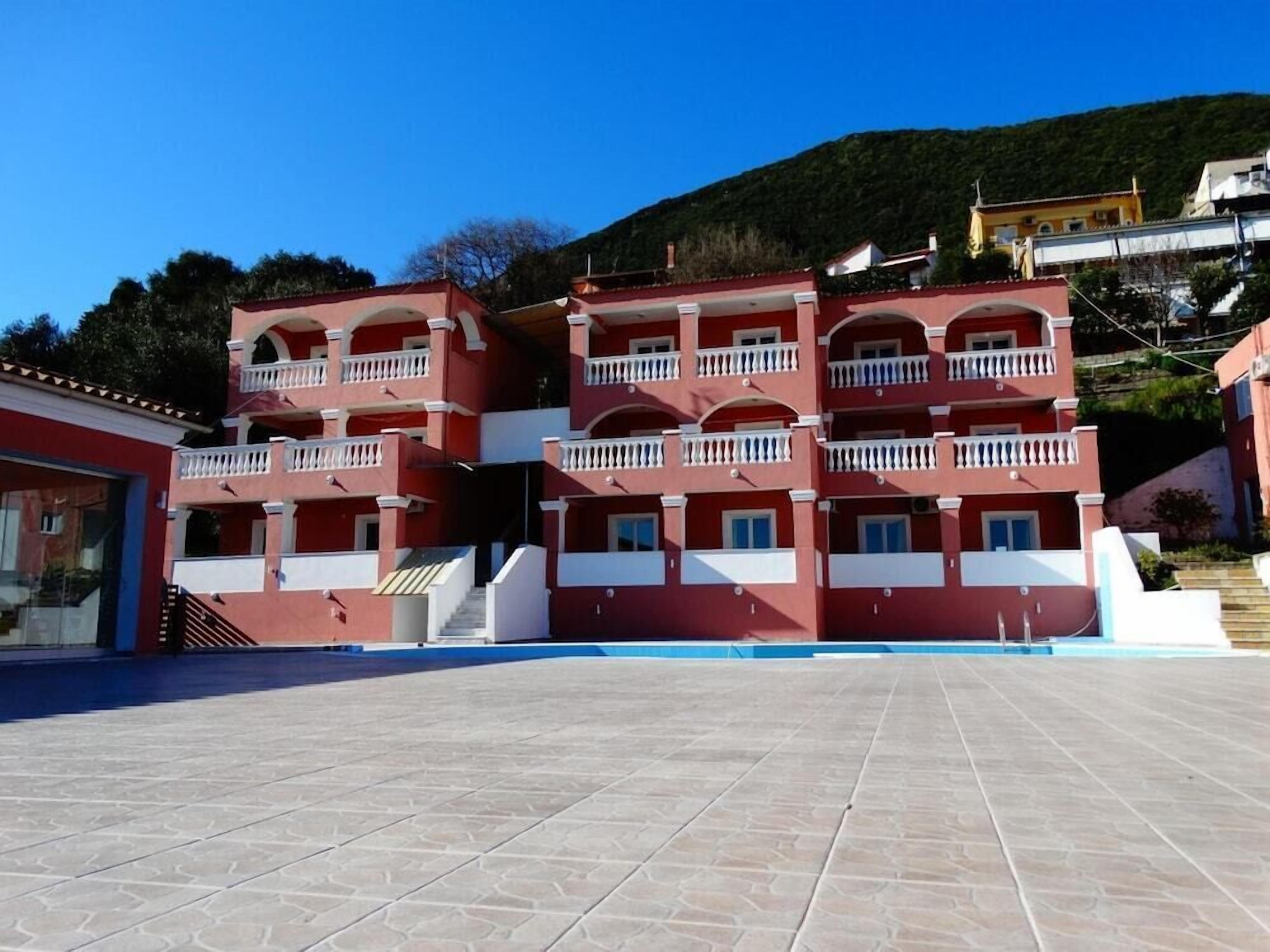 Un edificio rosso con diversi balconi e un cortile piastrellato.