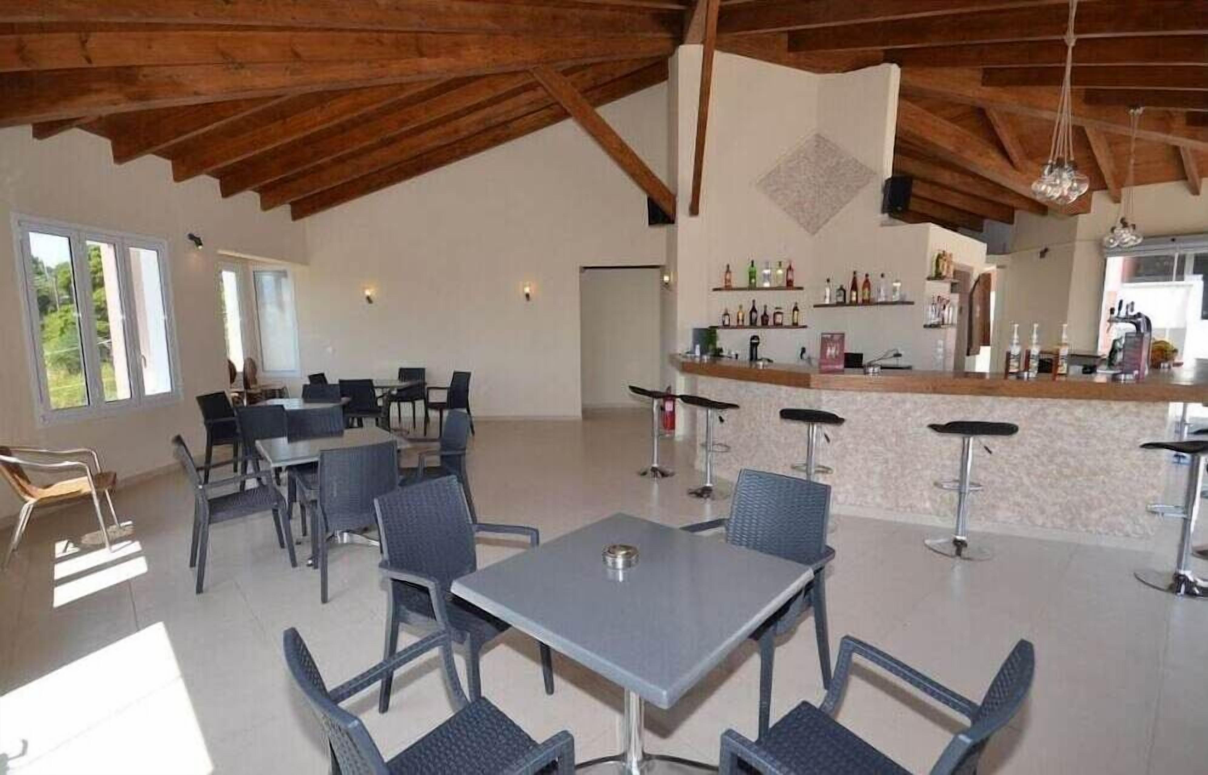 A spacious dining area with high ceilings and natural light, featuring multiple tables and chairs.