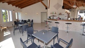 A spacious dining area with high ceilings and natural light, featuring multiple tables and chairs. - Paradiso Apartments (Corfu)