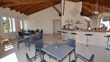 A spacious dining area with high ceilings and natural light, featuring multiple tables and chairs.