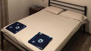 Un dormitori amb un llit, una taula de nit, un quadre i una làmpada al sostre.