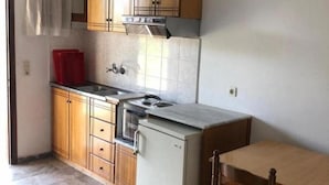Una cuina compacta amb armaris de fusta, forn integrat i nevereta petita.