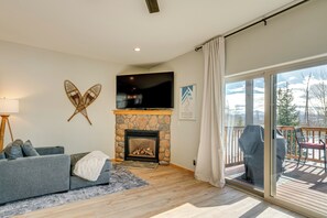 Relax by the fireplace in this cozy living room, featuring a flat-screen TV and comfortable sofa.