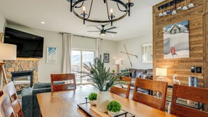 A dining area with a wooden table, chairs, a chandelier, a fireplace, and a television. - 8 Mi to Keystone: Mtn-View Ski Retreat! (Silverthorne)