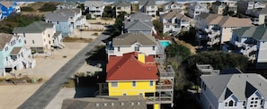 Uma área residencial à beira-mar, com casas, vista clara da praia e uma estrada que leva até ela.