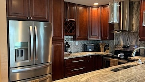 A modern kitchen with dark wood cabinets, stainless steel appliances, and a marble countertop.