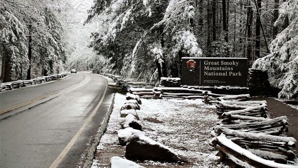 Strada che conduce al Parco Nazionale delle Great Smoky Mountains, con un cartello stradale e alberi imbiancati dalla neve.