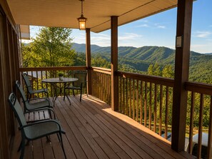 A wooden deck with a table and chairs, overlooking a mountainous landscape. - Gatlinburg, Autumn Leaves, Great Mountain Views, Hot Tub, Pool Table, Fireplace. (Gatlinburg)