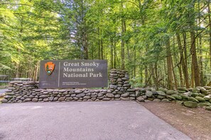 Un panneau indiquant l’entrée du parc national des Great Smoky Mountains, avec un mur de pierres et une forêt dense en arrière-plan.