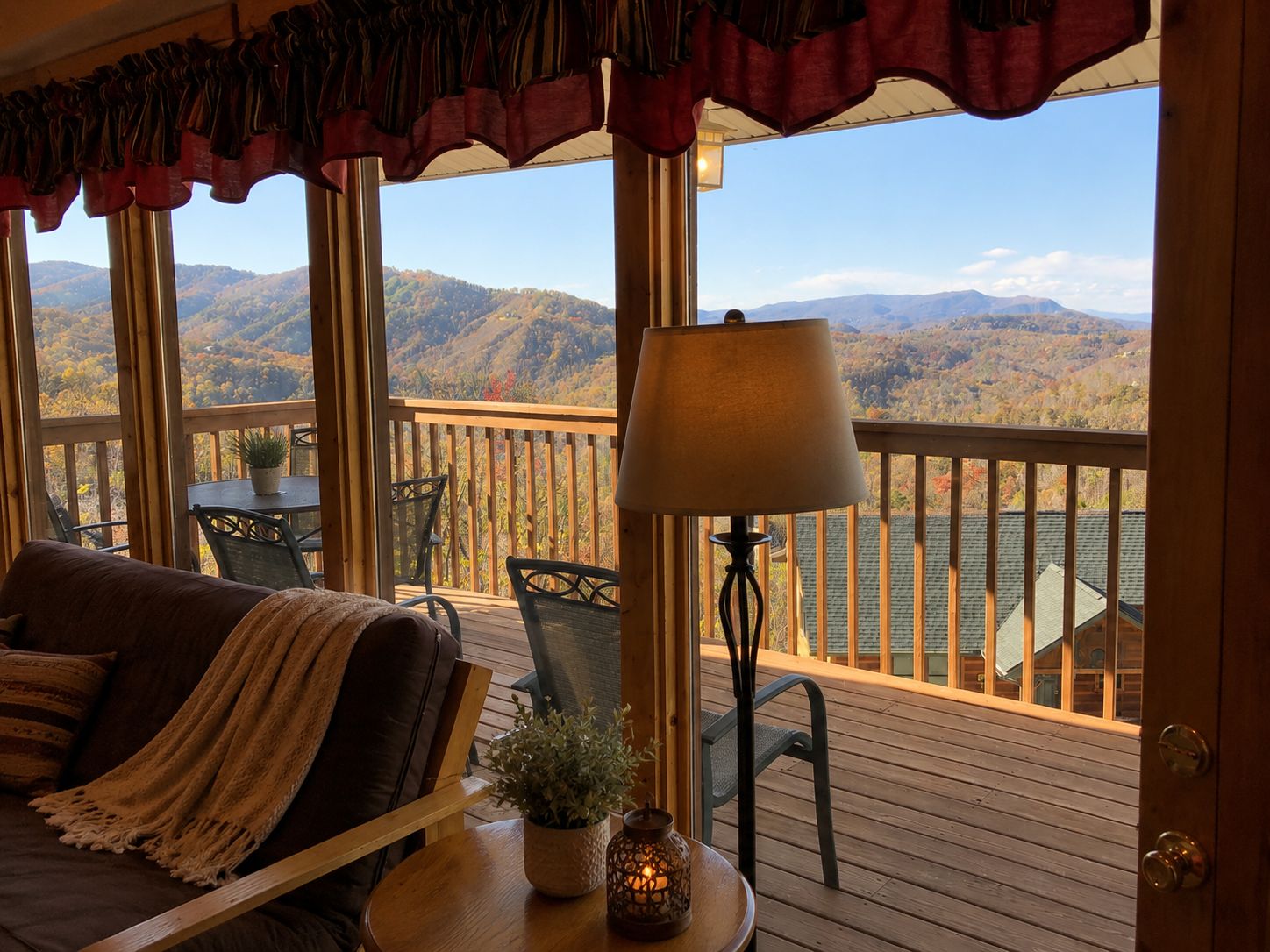 Ein gemütliches Zimmer mit Seeblick und Bergblick, ausgestattet mit einer Holzdiele, einem Sofa und einem Tisch mit einer Lampe.
