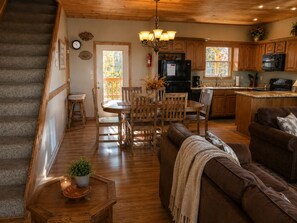 Une cuisine spacieuse avec des meubles en bois, un coin repas comprenant une table et des chaises en bois, un canapé en cuir marron et un escalier menant à un autre niveau.