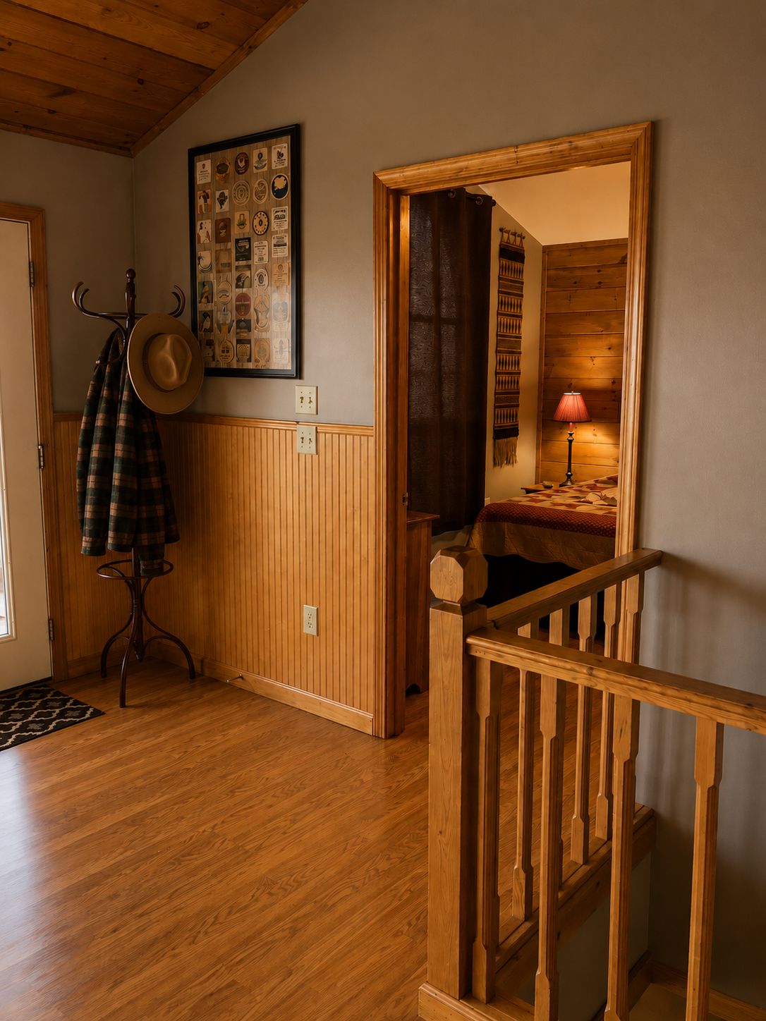 A wooden-floored hallway with a coat rack, a hat, and a framed collection of vintage postcards.
