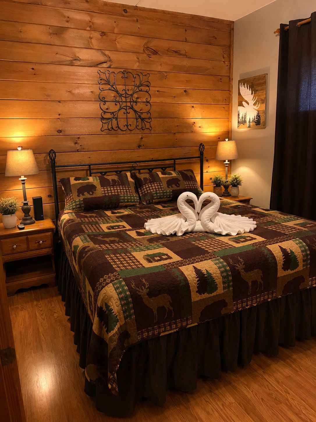A bedroom with a wooden headboard, a patterned bedspread, two bedside lamps, and a decorative wall piece.