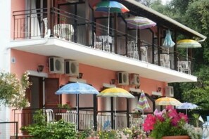 Un immeuble de deux étages doté de balcons, de climatiseurs et de parasols colorés.