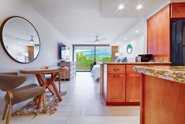 A modern kitchen with wooden cabinets, a granite countertop, and a dining area with a round table and chairs.