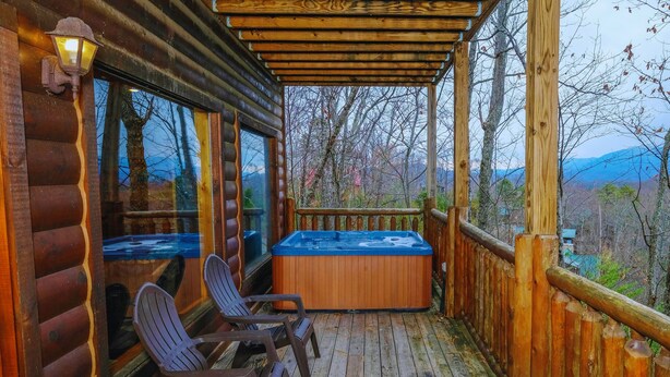 En træterrasse med et boblebad, to Adirondack-stole og et gelænder i træ.