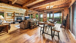 A rustic cabin interior with a stone fireplace, wooden furniture, and a balcony with a scenic view. - Long range unobstructed views! Privacy, Hot tub, Close to town. Check reviews. (Sevierville)