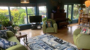 Relax in style with a comfortable sofa set, TV, and piano, surrounded by lush views and decorative touches.