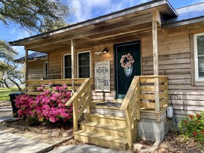 Step into our charming cabin-style retreat, featuring a welcoming entrance with a porch and a bench.
