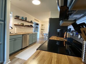 Enjoy cooking in this well-equipped kitchen with a central island, stainless steel range hood, and coffee machine.