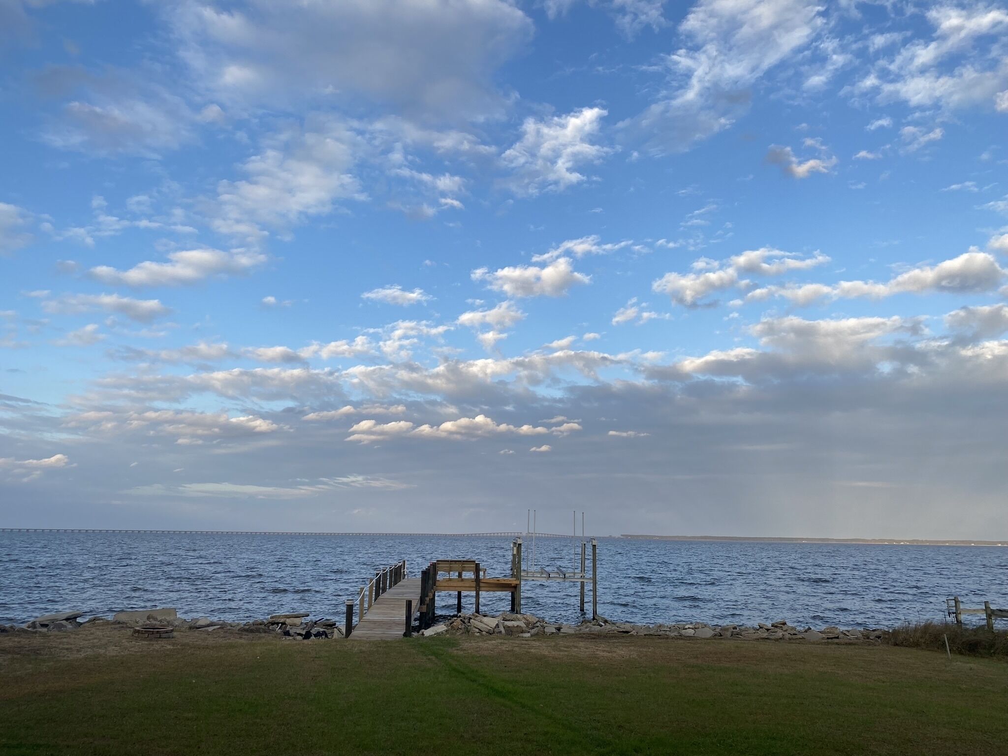 A wooden pier extending into a body of water with a clear sky above.