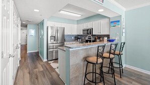 A modern kitchen with white cabinets, stainless steel appliances, and a central island with bar stools.