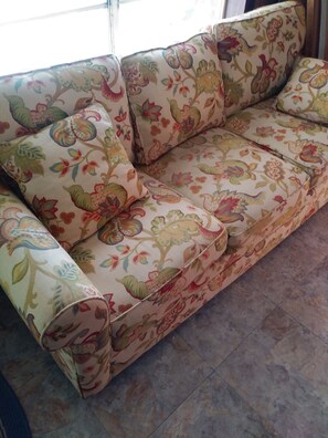 Ein Sofa mit floralem Bezug in einem Raum mit Fliesenboden.