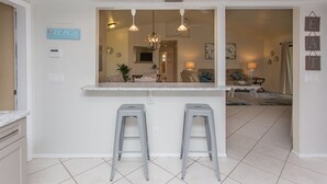 Een keuken met een centraal eiland, twee barkrukken, en een bordje met daarop 'BEACH'.