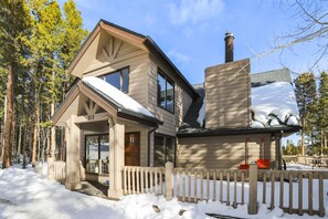 Una casa de dos pisos con fachada de madera y techo cubierto de nieve.