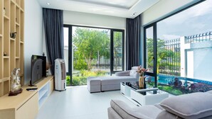 Ein modernes Wohnzimmer mit großem Fenster, einer Couch, einem Fernseher und einem Bücherregal.