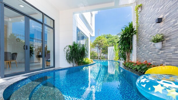 Ein moderner, überdachter Pool mit klarem, blauen Wasser, umgeben von Topfpflanzen und einem gelben Schwimmreifen.