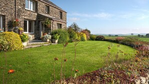A stone house with a well-maintained lawn and flower beds. - High Butterbent Cottage -  Rural cottage that sleeps 6 guests  in 3 bedrooms (Kendal)