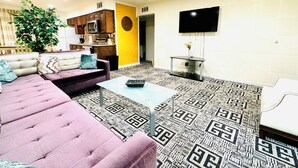 A living room with a sofa, coffee table, and a TV mounted on the wall. - Condo,2Bedrooms,Sale,Strip,BOOK,Las Vegas,LVCC,wifi,SALE,pool,SemaShow,Labor Day (las vegas)