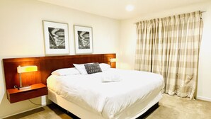 A neatly made bed with white linens, two framed pictures on the wall, and a nightstand with a lamp. - Condo,2Bedrooms,Sale,Strip,BOOK,Las Vegas,LVCC,wifi,SALE,pool,SemaShow,Labor Day (las vegas)