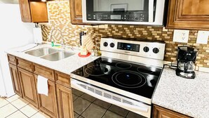 A kitchen with wooden cabinets, a microwave, a stainless steel stove, and a coffee maker. - Condo,2Bedrooms,Sale,Strip,BOOK,Las Vegas,LVCC,wifi,SALE,pool,SemaShow,Labor Day (las vegas)