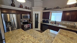 A kitchen with granite countertops, stainless steel appliances, and dark wooden cabinets. - Cozy Island House with Heated Pool (Lake Havasu City)