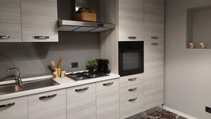 Een moderne keuken met een RVS spoelbak, een gasfornuis en een inbouwoven.