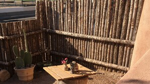 A rustic outdoor seating area with a wooden table and benches, surrounded by a wooden fence and potted plants. - Casa de San Pasquale, 1800s restored terones adobe (Albuquerque)